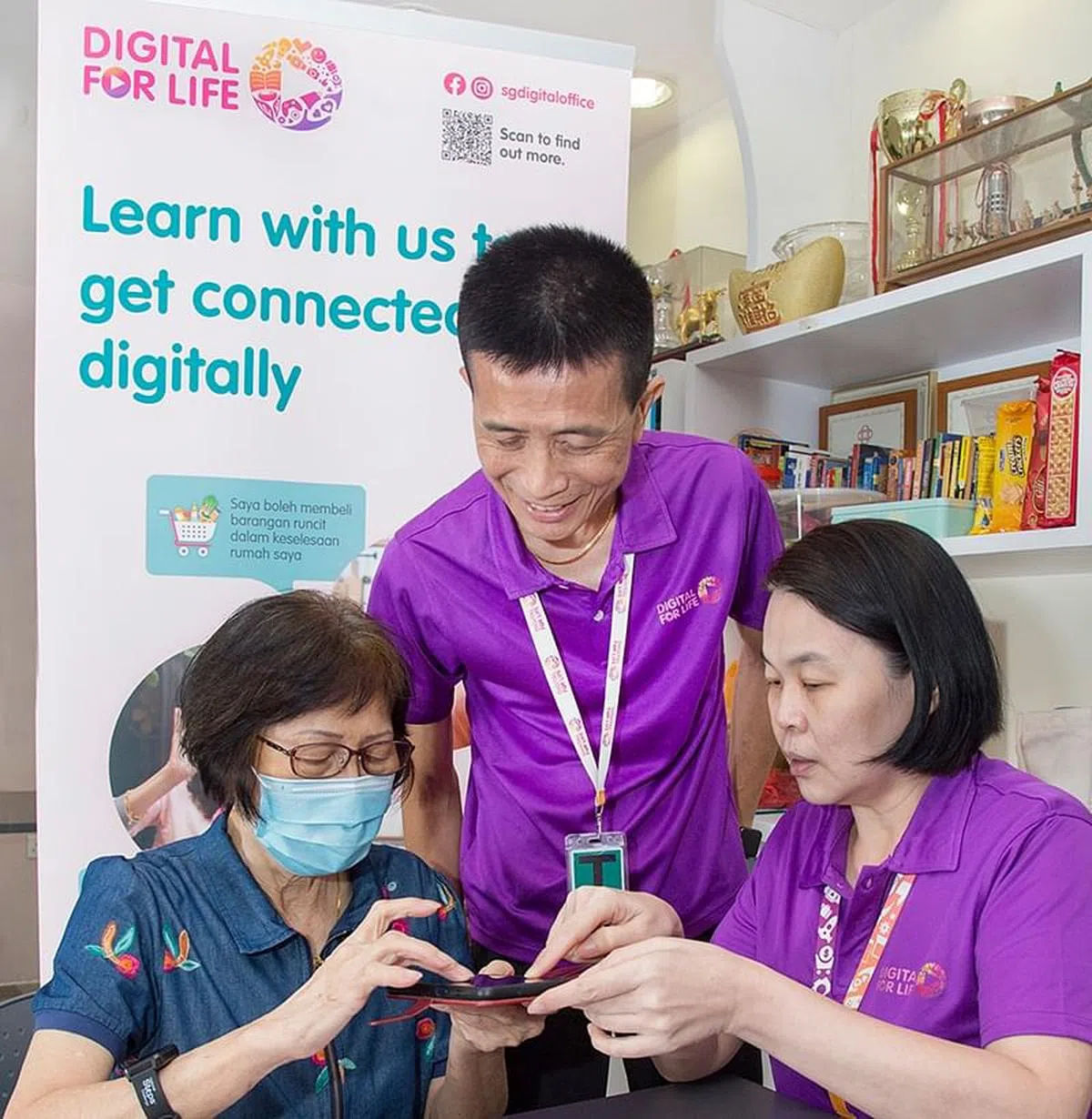 张锦源（中）带领团队帮助其他乐龄学习使用智能产品。（图/新报业媒体）