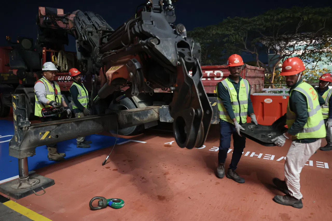 工作人员协力组装起重机，包括放置底盘，确保起重机稳固。（李冠卫摄）