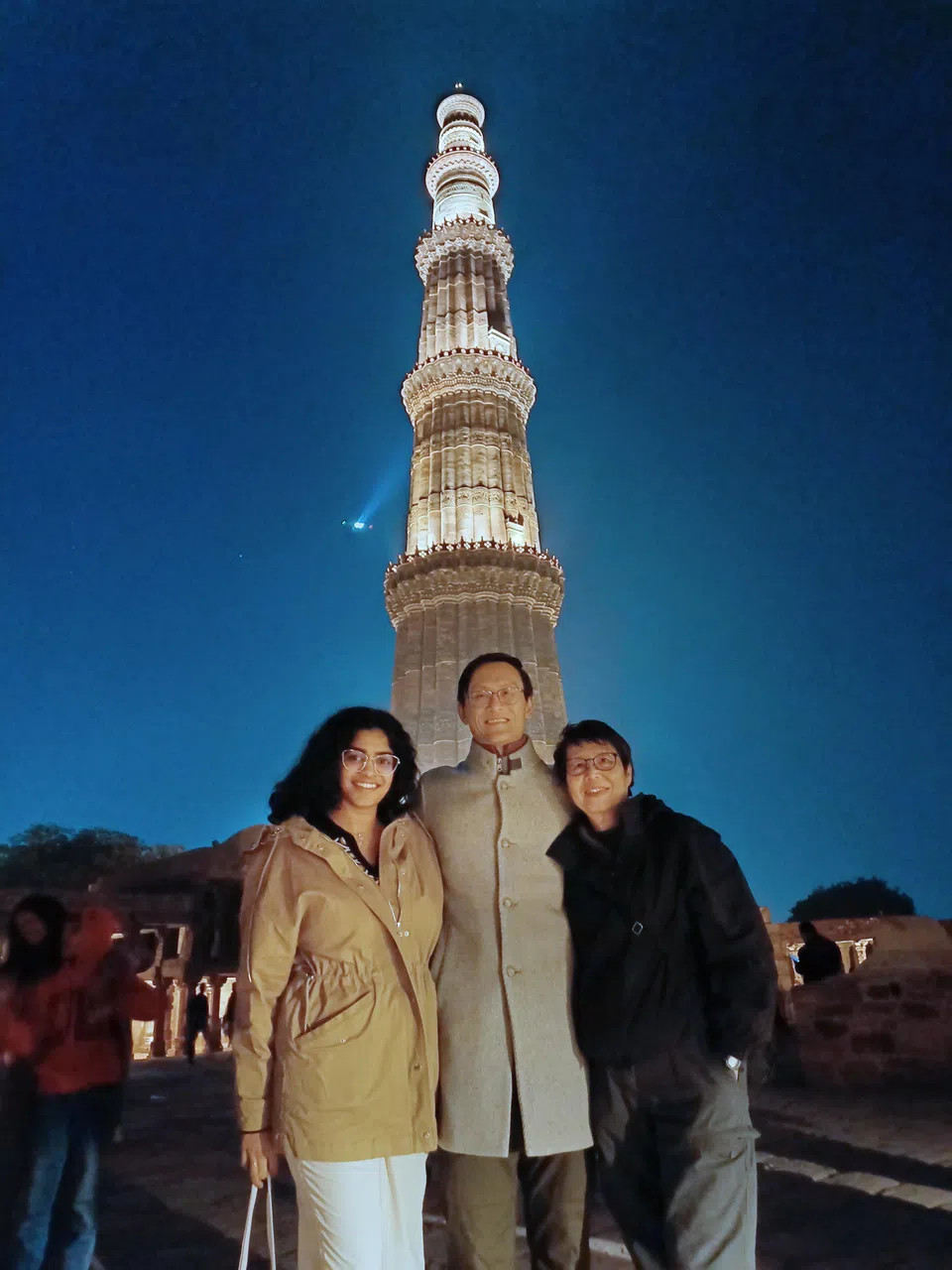 在印度新德里工作的邓简兮（中）和女朋友（左）和母亲（右）参观拥有900年历史的联合国教科文组织世界文化遗产顾特卜塔。他说，这座60多米高的塔由红色砂岩和大理石建成，在灯光照射下，塔身上精美的设计构成令人惊叹的美丽景象。（受访者提供）