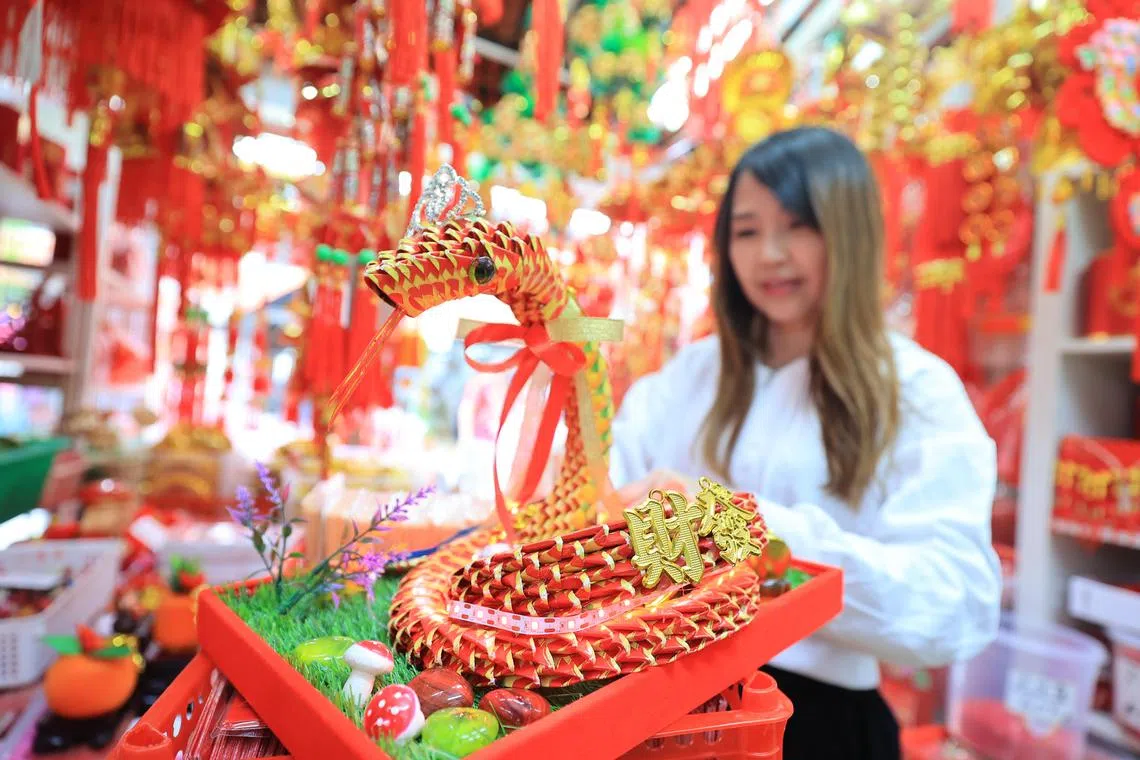 在大巴窑邻里经营年货饰品店的曾秀芬说，已陆续接到很多顾客的新年订单，正在加班为客人赶制蛇年手工艺品。（唐家鸿摄）