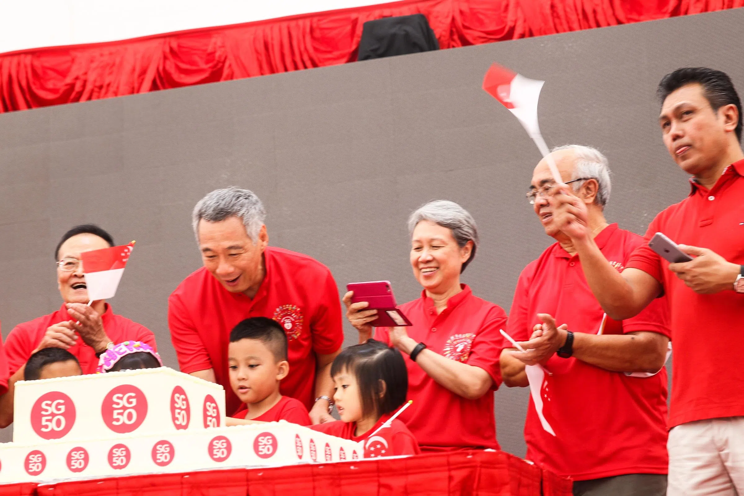 2015年8月9日，李总理（左二）和夫人何晶（左三），在宏茂桥德义区的国庆敬礼仪式上，受邀上台切SG50金禧国庆蛋糕。（新明日报）