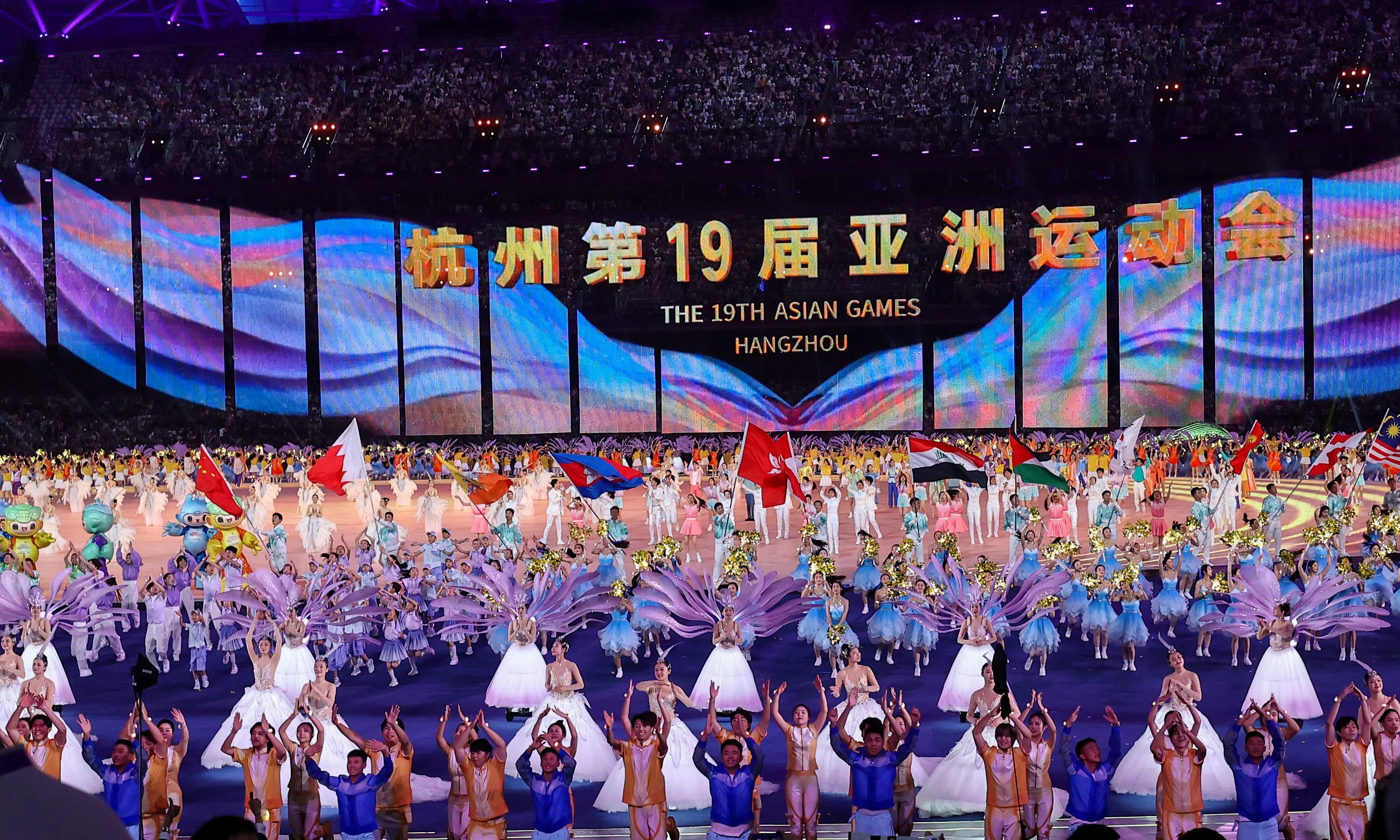 表演者载歌载舞，参赛国家和地区的旗帜在场中央一字排开。（陈渊庄摄）