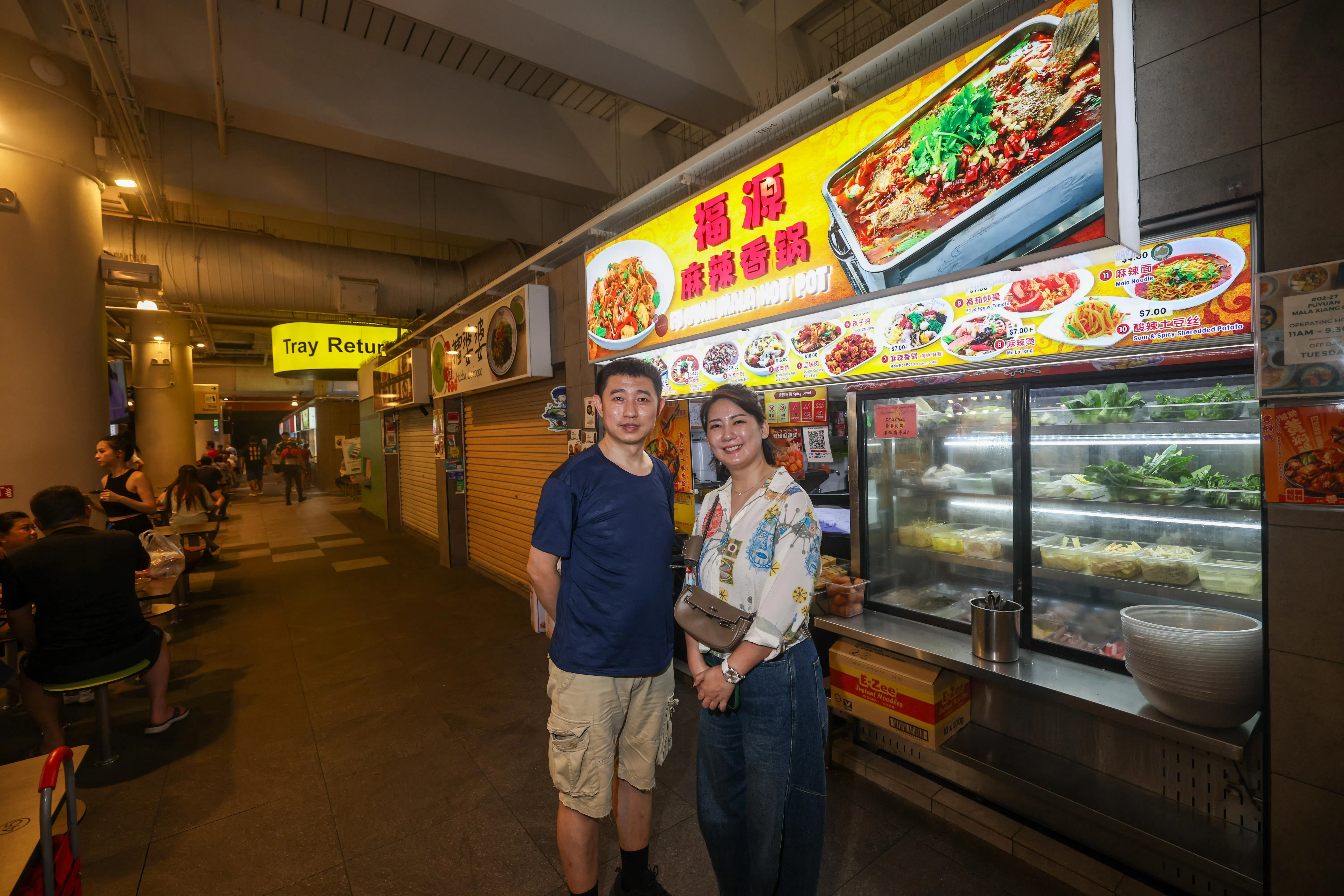 关明哲（右）和丈夫经营麻辣香锅生意10年，之前开过多家分店，如今只剩在榜鹅综合社区中心小贩中心的一家。为了让老顾客们能吃到熟悉的味道，他们希望能继续长久经营下去。（陈渊庄摄）