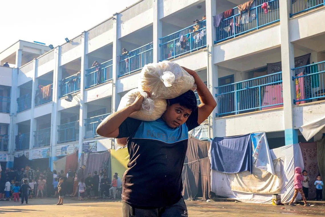 加沙地带的粮食目前仅从拉法（Rafah）运入。11月14日，在拉法一所由联合国难民救济处管理的学校里，一个男孩抬走他所配得的粮食。（法新社）