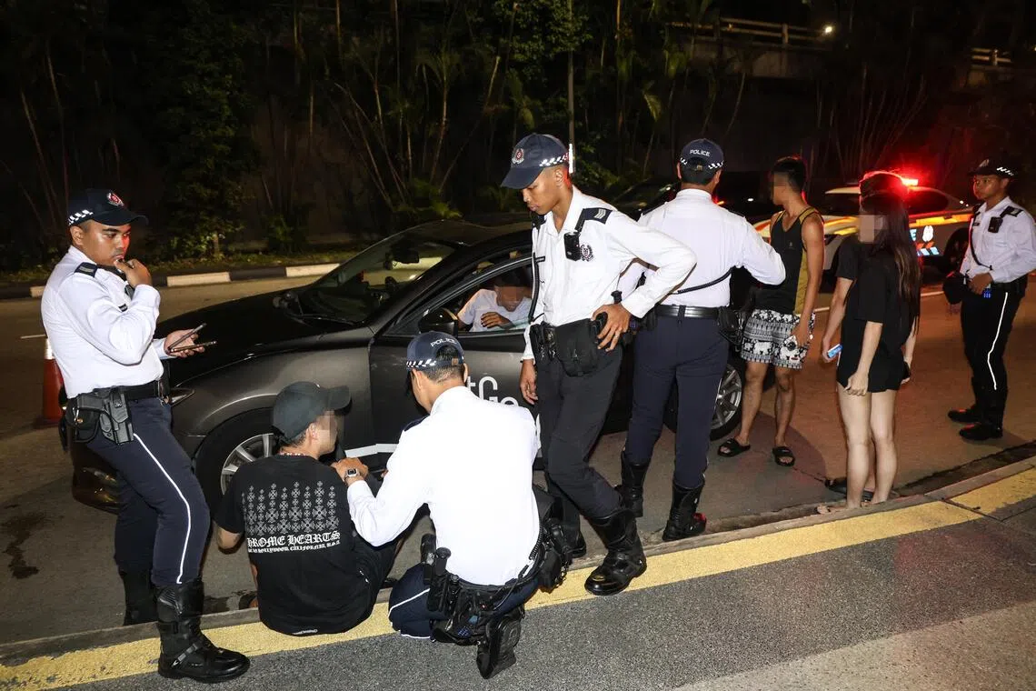 一名驾驶共享汽车的男子（左二）被查出是通缉犯，当场被捕。车上的四名男女乘客，也一一下车接受问话。（关俊威摄）