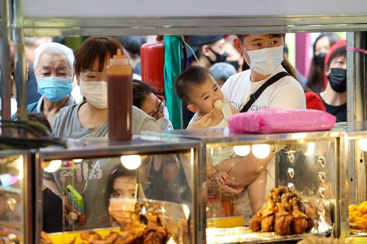 在宏茂桥流动市集开放首日，陆俊伟（右一）带妻儿逛市集，买了鱼丸等小吃，一饱口福。（蔡家增摄）