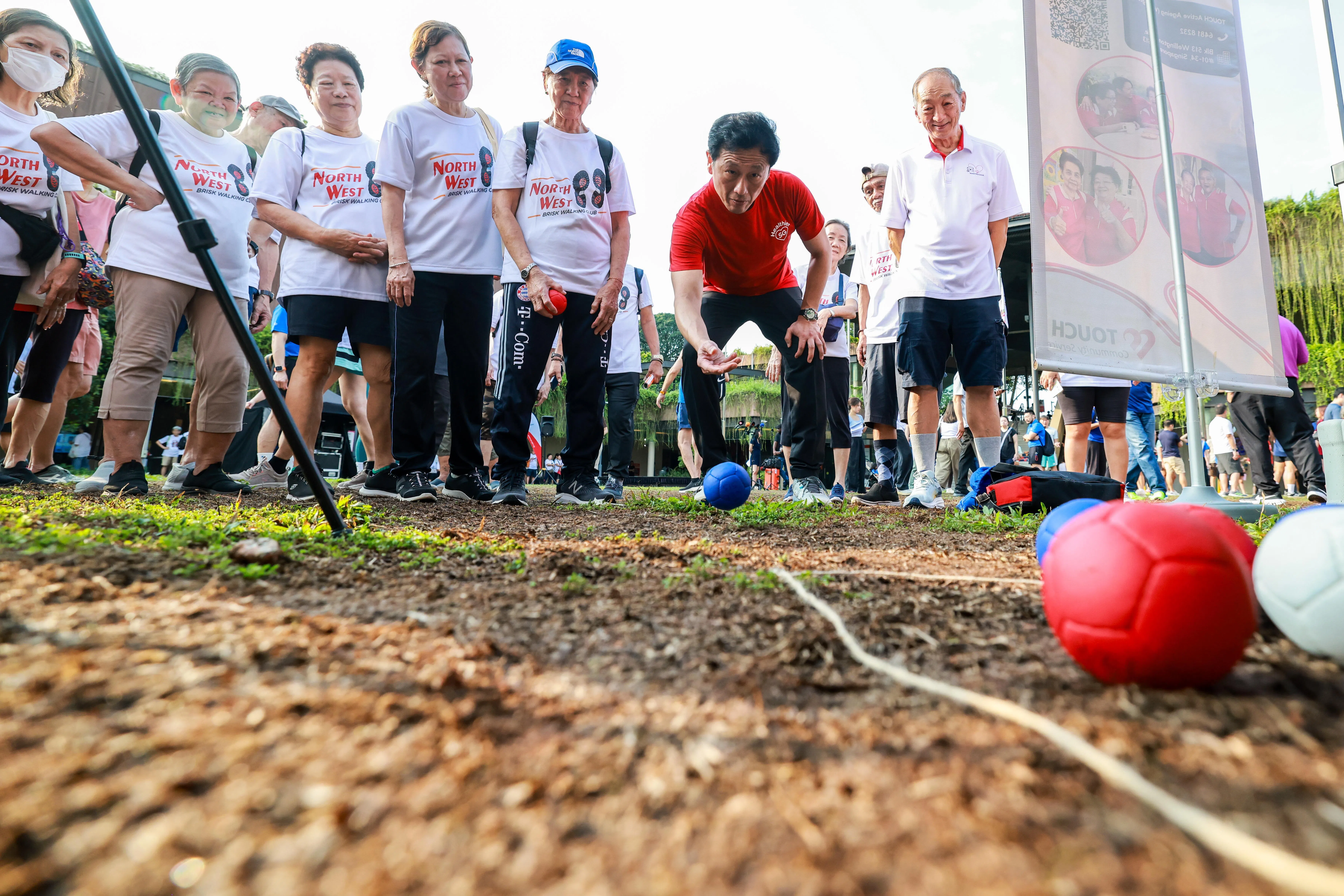 社会政策统筹部长兼保健卫生部长王乙康（红色上衣）完成快走后，也参与现场的保健活动，和居民们互动，并鼓励大家积极动起来。（陈斌勤摄）