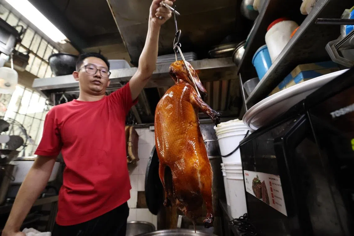 谭耀恒选用约2.8公斤的马来西亚鸭，先腌制、上色并风干定型，再以慢火烤至金黄酥熟。上桌前淋上热油，让鸭皮更紧实香脆。（梁麒麟摄）