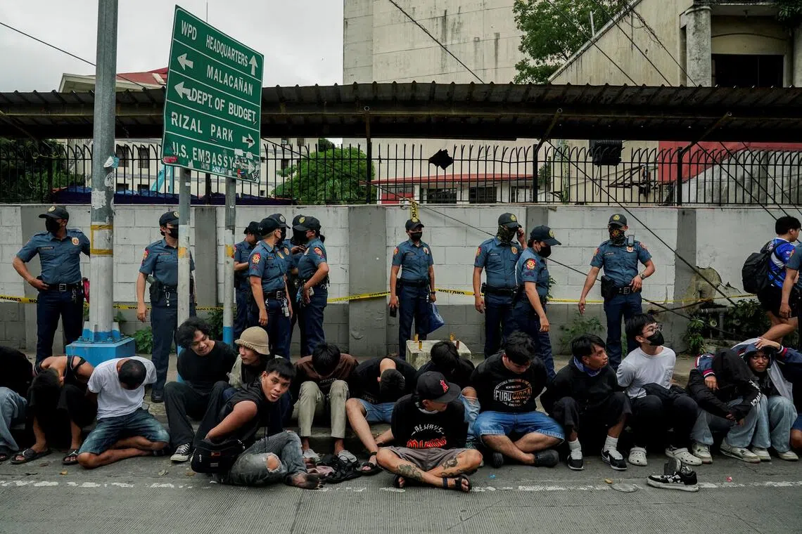 菲律宾首都马尼拉星期天（9月21日）爆发大规模示威。一些抗议者被警方拘捕后，铐着双手坐在马路边，他们大多数都是年轻人。（路透社）