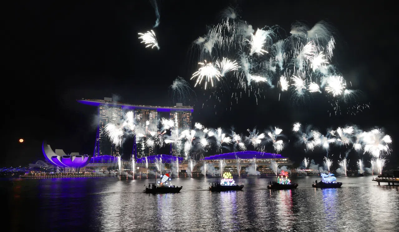 璀璨烟花映照着艺术科学馆和滨海湾金沙等新加坡地标，水面上漂浮着由特需艺术工作者设计的创意花车，为庆典增添独特风采。（李天錡摄）
