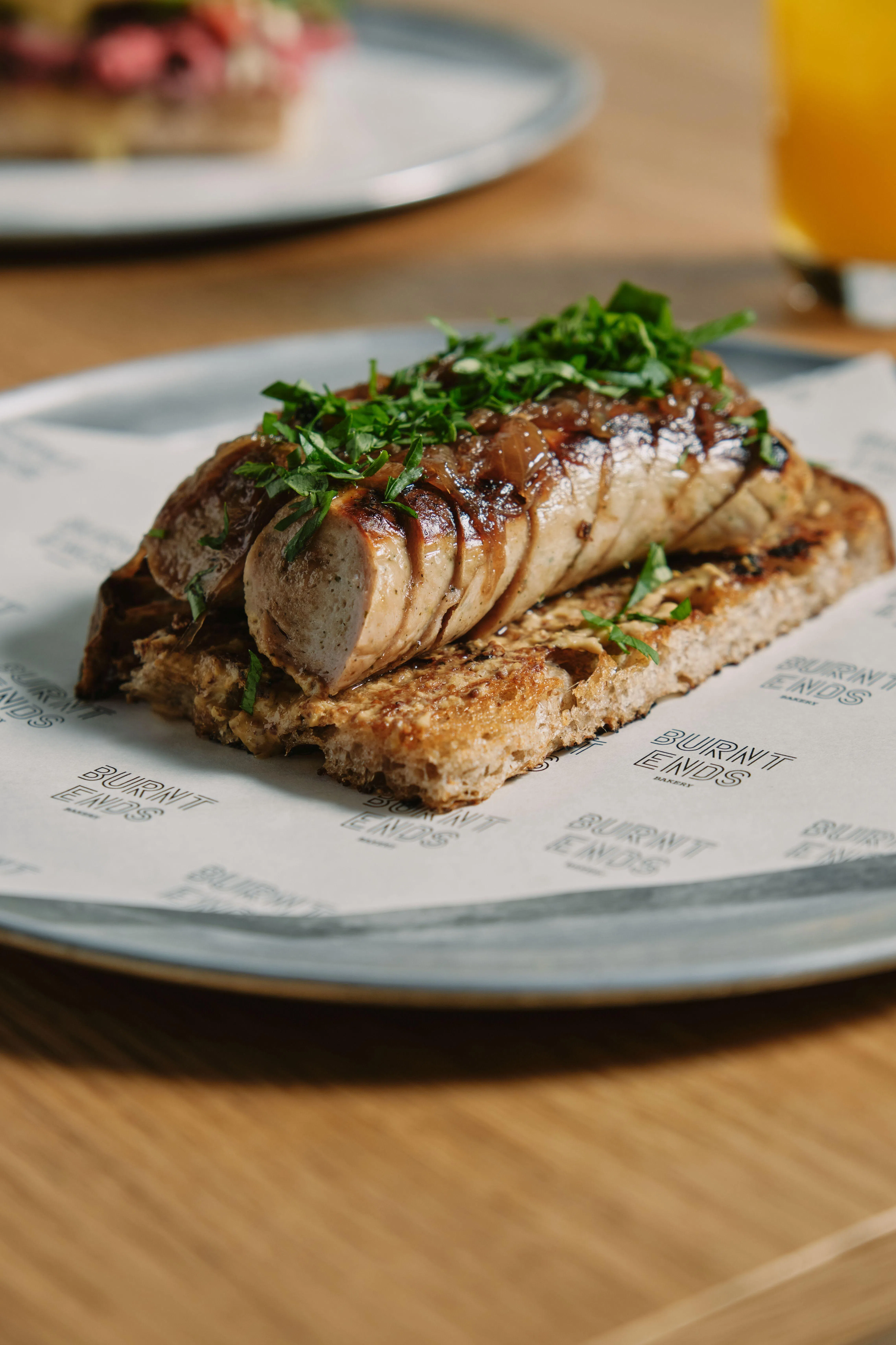 巴伐利亚香肠放在烤酸种面包上，再淋浓郁红酒洋葱酱。（餐馆提供）