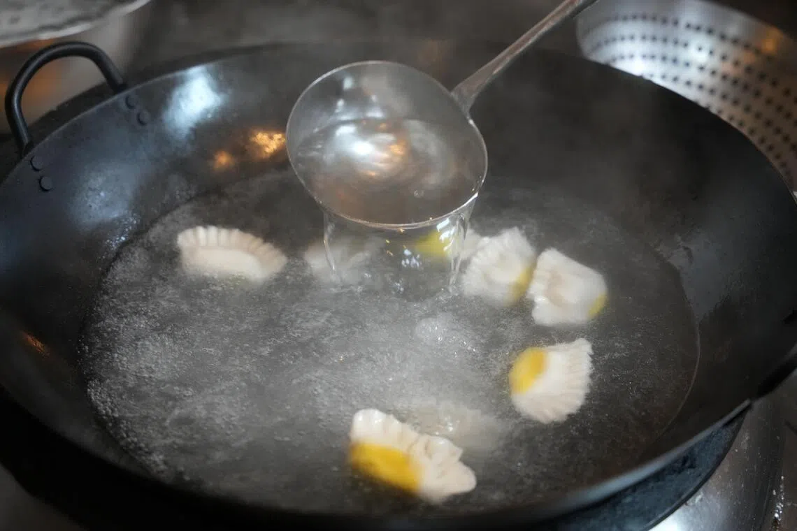 饺子下锅后，水开时分三次加入室温水，让饺子慢慢煮熟，保证皮薄馅嫩。（谢智扬摄）