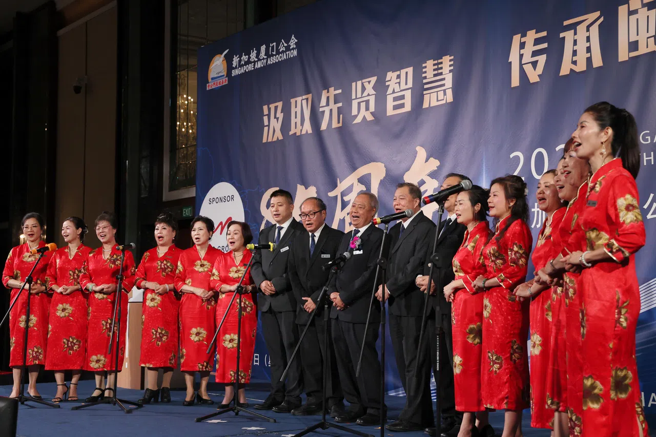 厦门公会会长汪家裕（左九）与公会多位领导及歌咏团，在台上演唱新会歌《心安所在是阮兜》。（龙国雄摄）