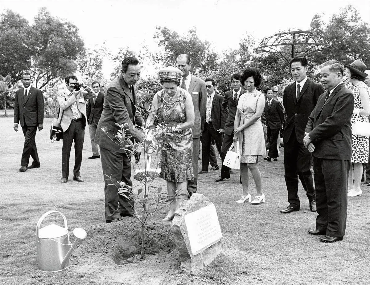 英女王伊丽莎白二世（中）与菲利普亲王（在她后方）1972年到访我国时，由裕廊镇管理局主席温华想（左）陪同，在裕廊的园地种下香灰莉木。（档案照片）