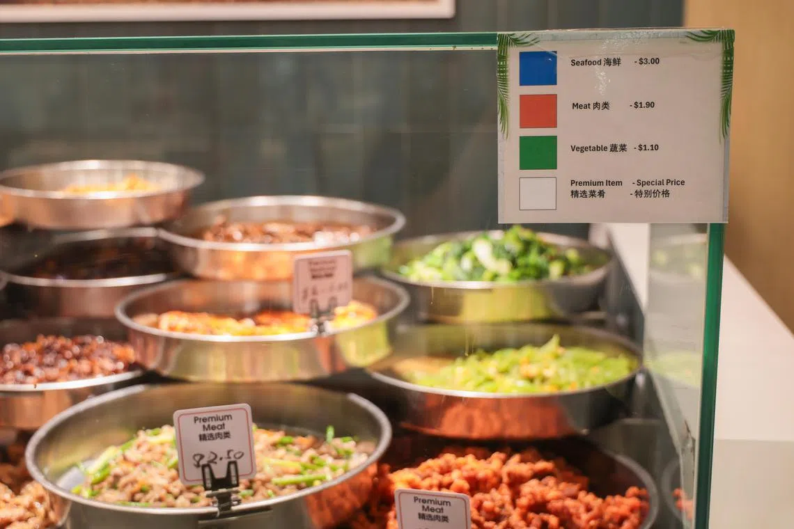 诺维娜广场的口福食阁杂菜饭摊，原先只为精选菜品贴上白色标签，并标明具体价格，档口前也张贴了说明图。但蔬菜、肉类和海鲜等一般菜品前，却不见对应的颜色标签。经食阁业者提醒，摊位已补齐颜色标签。（张俊杰摄）