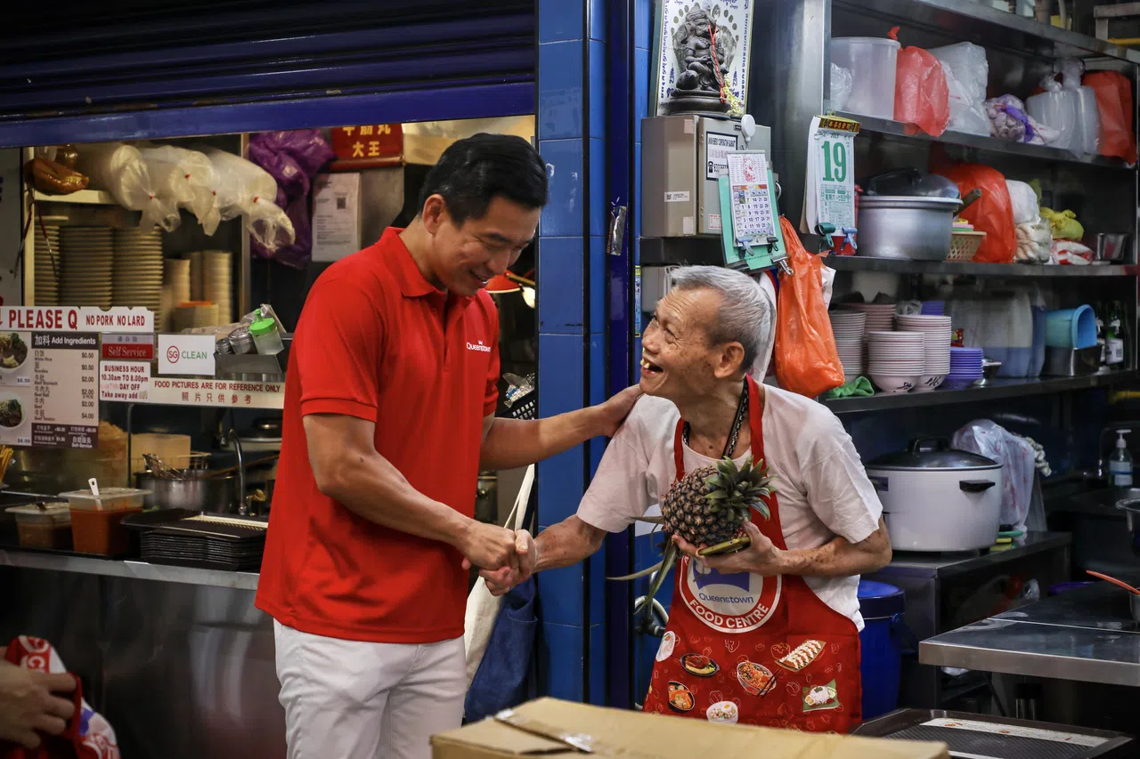 社会及家庭发展部兼律政部高级政务次长蔡瑞隆（左）出席亚历山大村美食中心翻新后的开幕式。他在现场与经营摊位多年的摊主互动。（张恺恩摄）