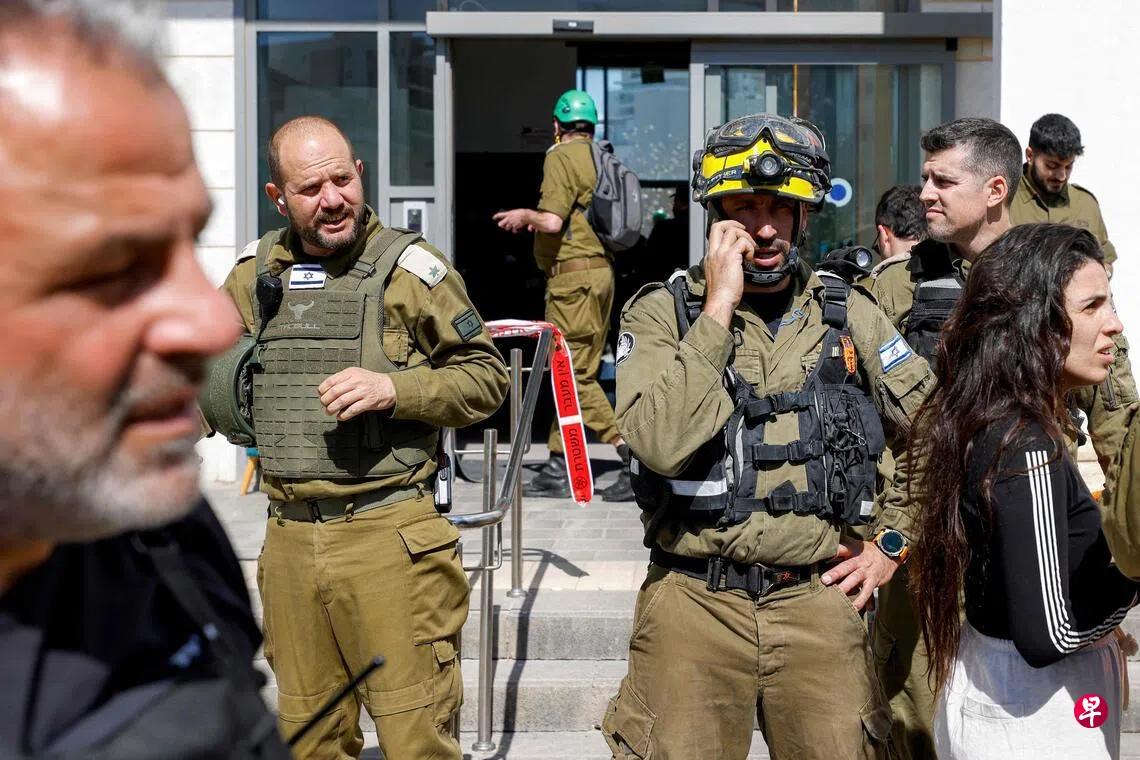 Image 15: 2月28日，以色列北部城市提拉特卡梅尔一栋楼被导弹击中，居民撤离大楼，以军在现场警戒。 （法新社）