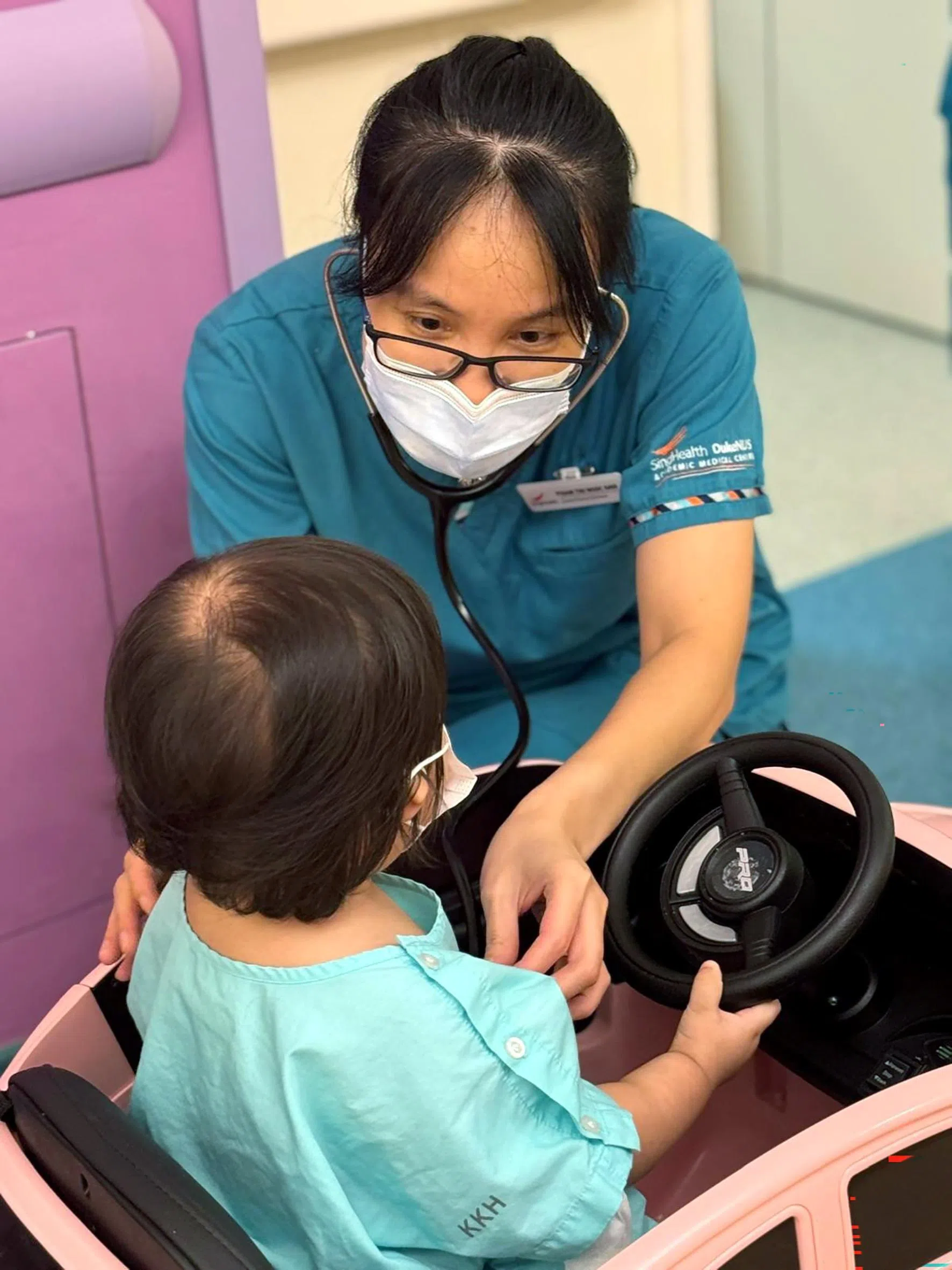 总统护士奖得主、竹脚妇幼医院资深临床护士兼临床专科护理师范氏玉英（右）在儿科肿瘤病房，用听诊器听儿童患者的心跳。（竹脚妇幼医院提供）