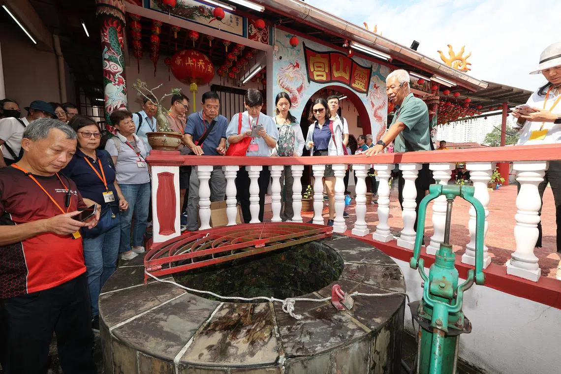 新加坡文史达人李国梁（右二，绿衣者）向参与者讲解陈厝港的历史，包括灵山宫的这口井是居民当年为取干净饮用水而挖的。（唐家鸿摄）