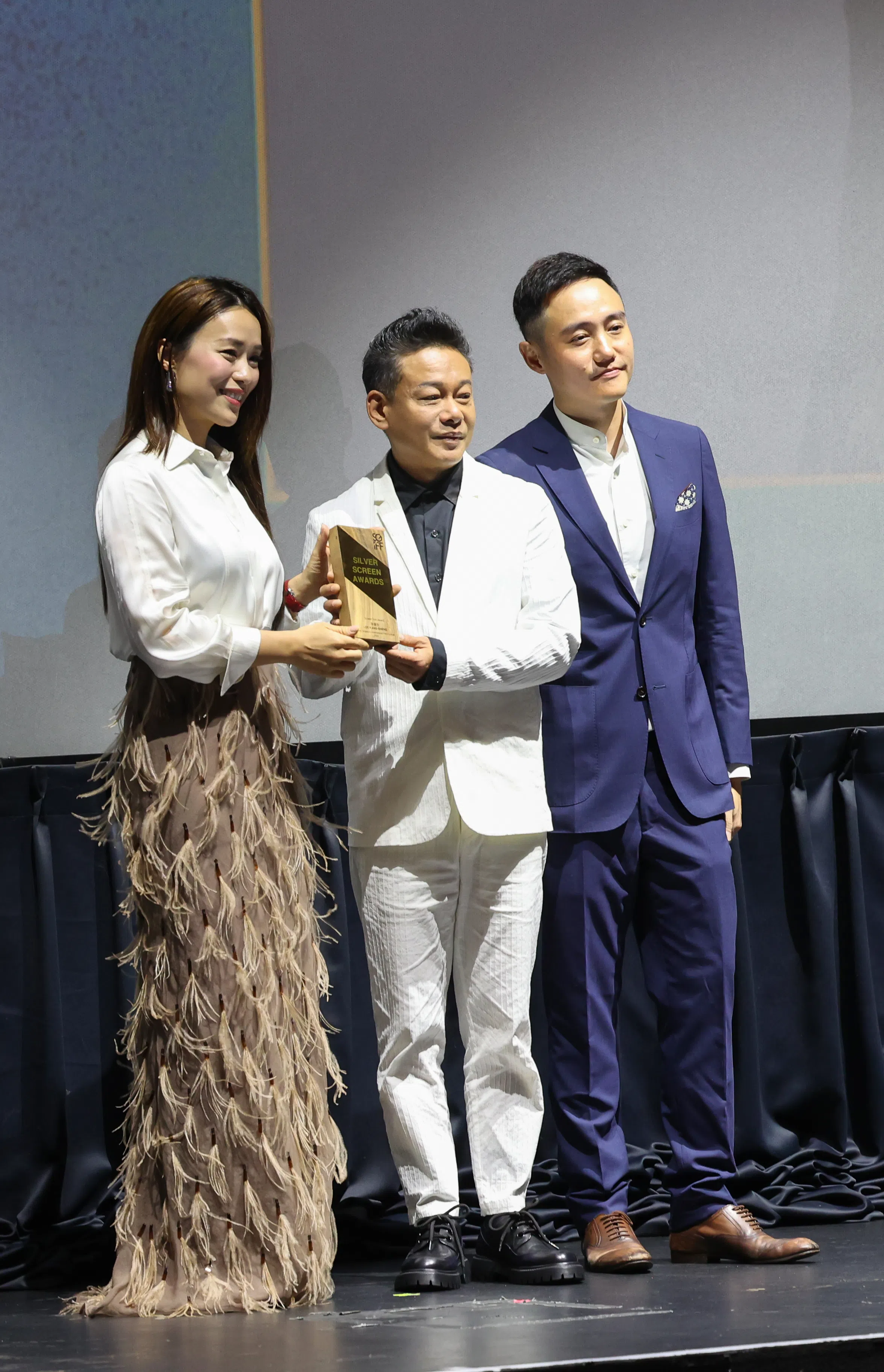 李康生（中）从SGIFF35大使林慧玲（左）手中接获大奖，右为电影节筹委会主席巫俊锋。（龙国雄摄）