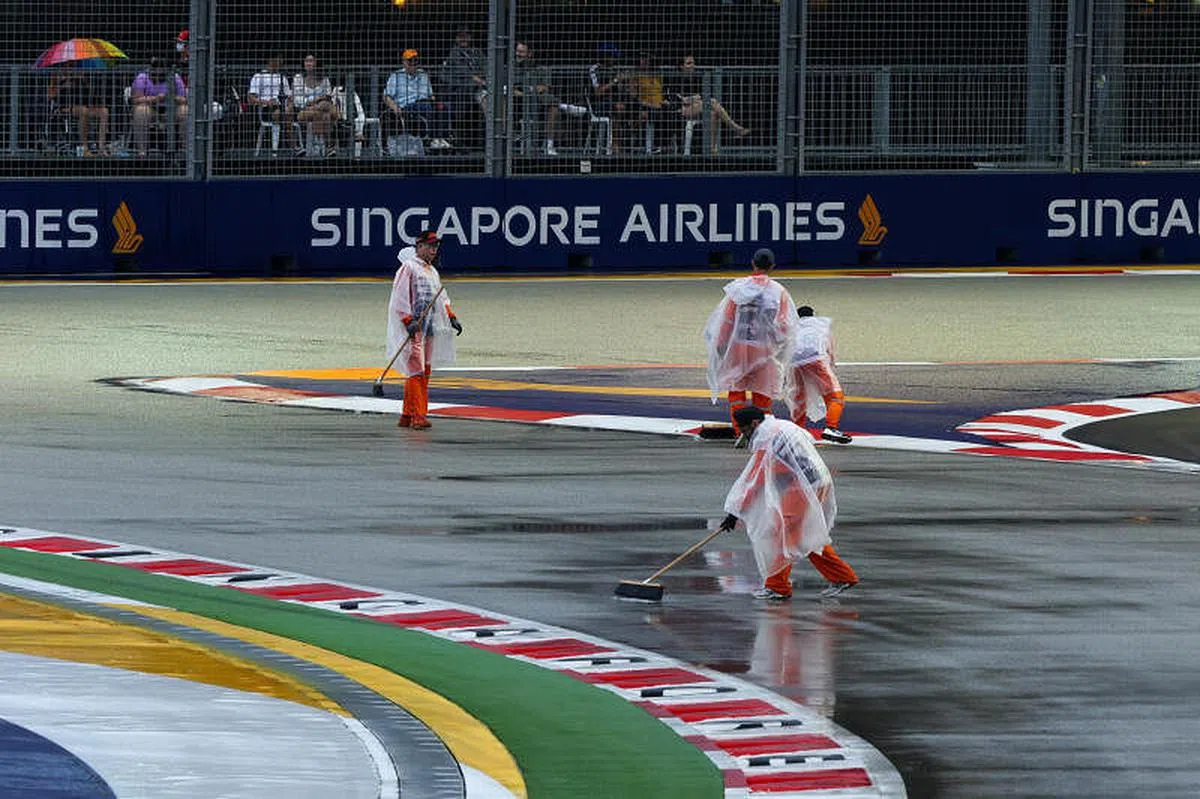 工作人员在雨后拿拖把清理赛道，散开积水。（张思庆摄）