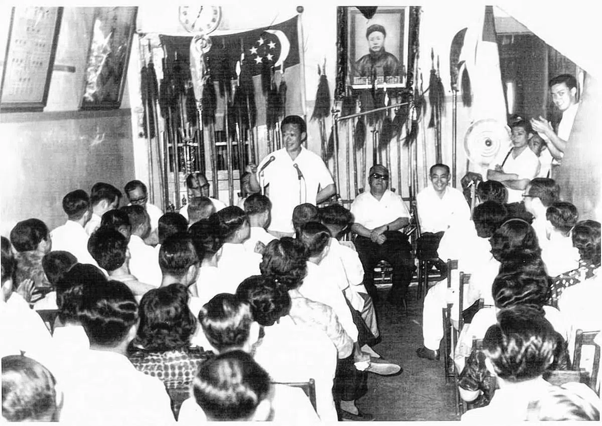 新加坡独立时，总理李光耀（面对镜头站立者）在精武体育会呼吁年轻人参加义勇军，墙上的照片为祖师爷霍元甲。（精武体育会照片）