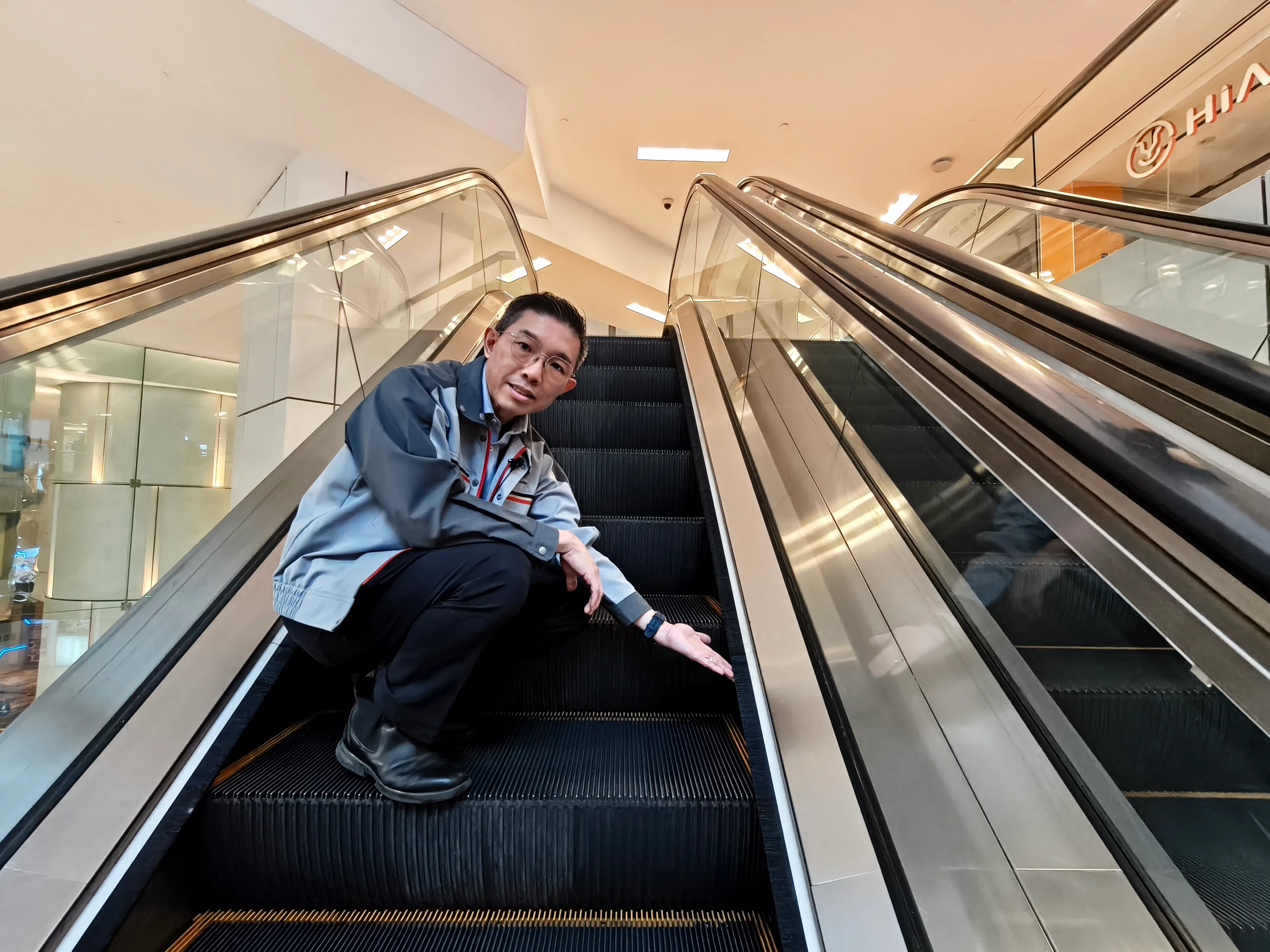 三菱电梯外勤服务部副经理吴仁杰在扶梯上解说毛刷的真正功用。（陈默汎摄）