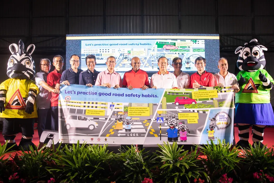 内政部长兼律政部长尚穆根（左六）星期六晚间为公路安全横幅主持推介。左三起是陆路交通管理局运输及公路运作组高级总署长谢明德、交通警局局长陈新兴高级助理警察总监、内政部兼国家发展部政务部长费绍尔副教授、新加坡公路安全理事会主席郑桠光、人民协会总执行理事长卓荣能，其他是忠邦基层领袖。（特约沈康雄摄）