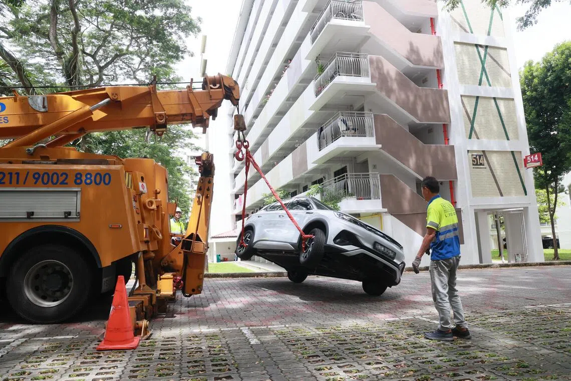 白色汽车被吊起后放回马路上。（潘丰源摄）
