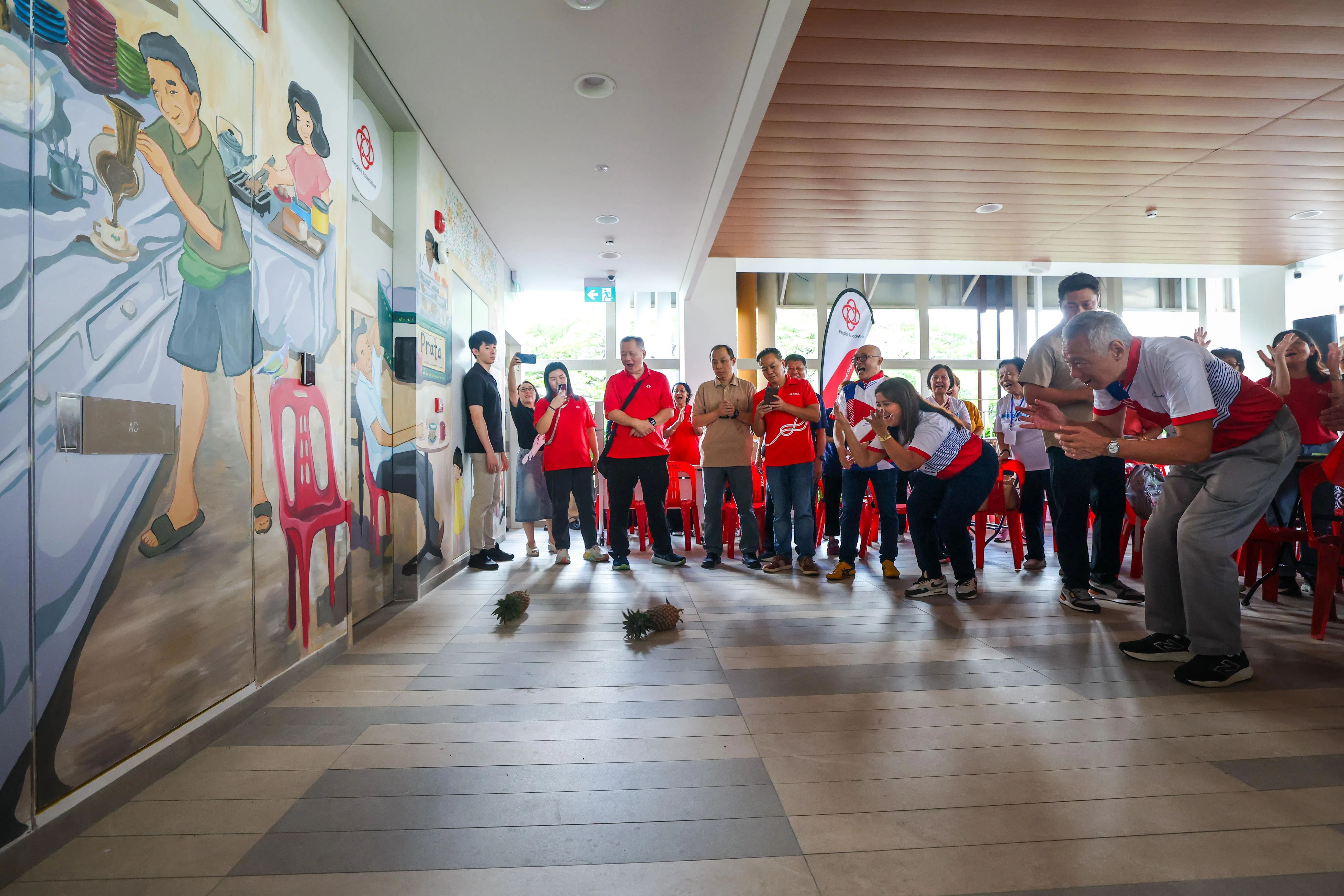 同为宏茂桥集选区议员的国务资政李显龙（前排右一）和娜蒂雅（右三）为翻新后的静山民众俱乐部主持开幕，并进行“滚黄梨”仪式，寓意好运滚滚来。（白艳琳摄）