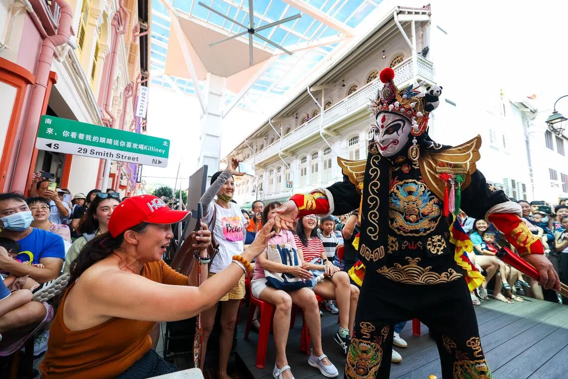 牛车水的史密斯街举办冬至庆祝活动，汇聚精彩表演与互动体验，让公众尽情感受传统节日的独特魅力，图为变脸演员与现场观众互动。（林明顺摄）
