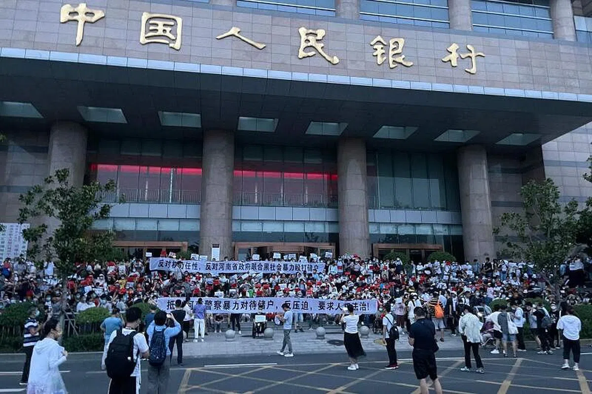 储户举着横幅于7月10日在郑州的中国人民银行分行前抗议。（法新社）