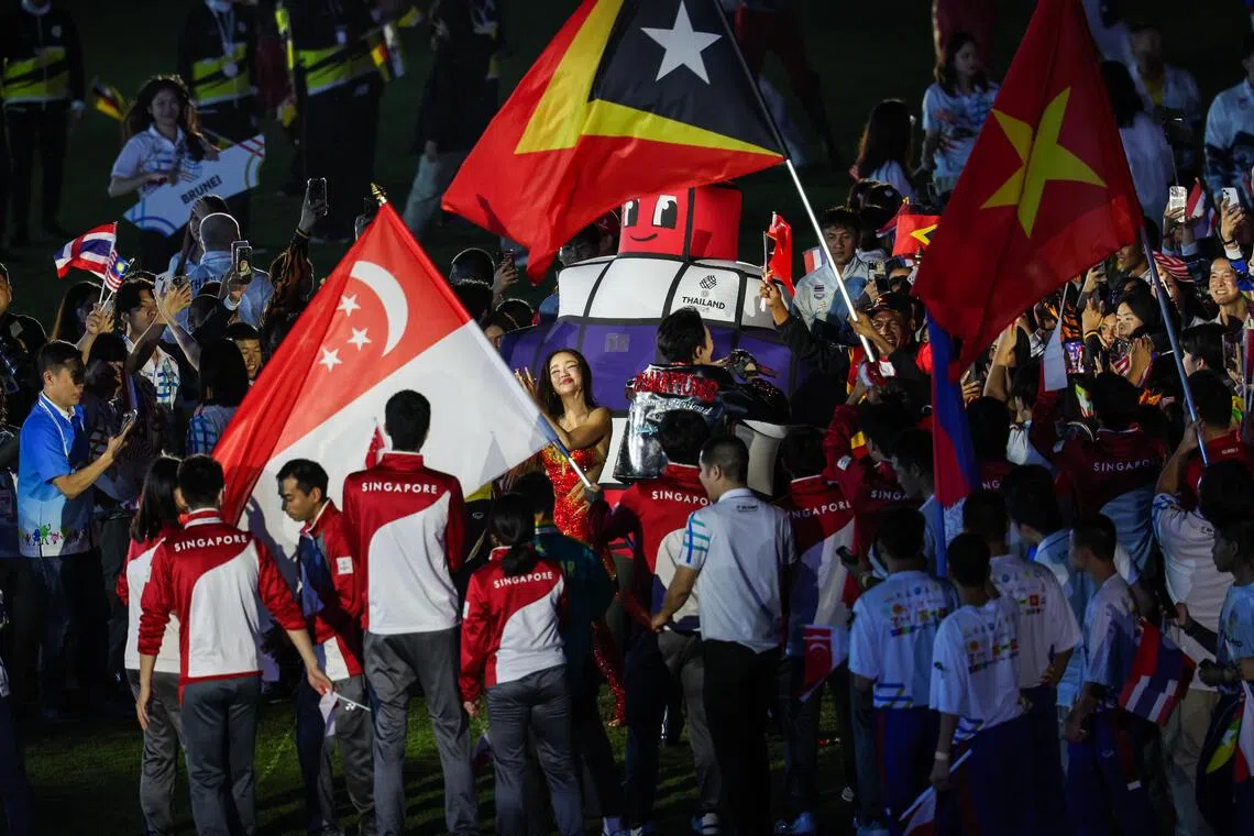 两名泰国歌手（中）也和本届东运会吉祥物一同来到新加坡和其他代表团之间，一同庆祝泰国东运会的比赛激情。（白艳琳摄）