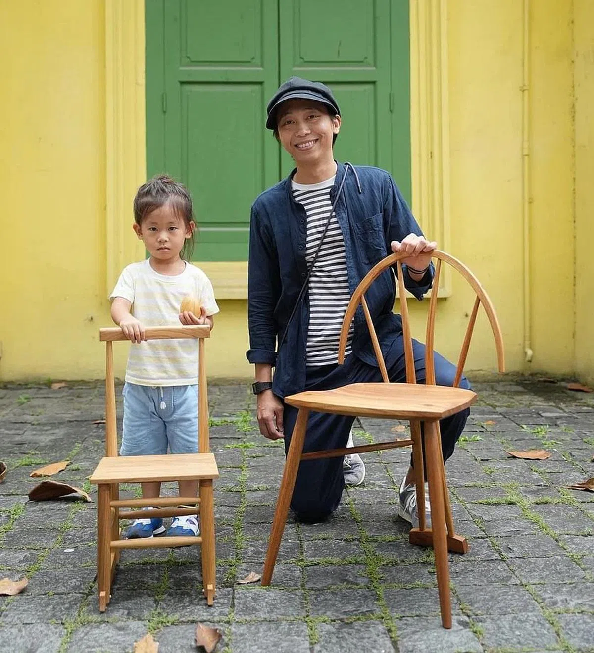 蔡金展（右）与他制作的大人椅、小孩椅及儿子手上的木蛋。（谢智扬摄）