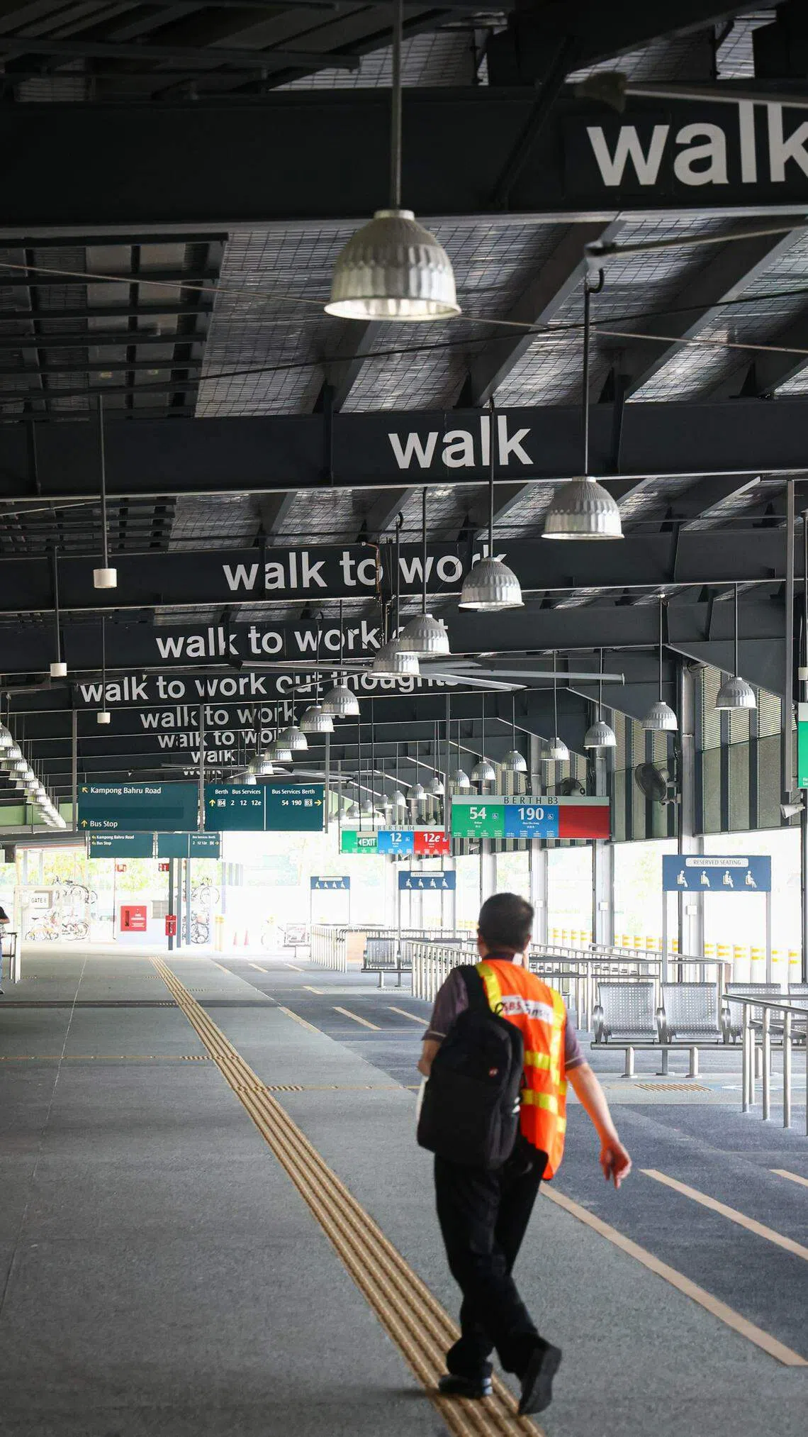 导演陈彬彬在甘榜峇鲁巴士总站的天花板横梁，与行走有关的文本装置。（李健玮摄）