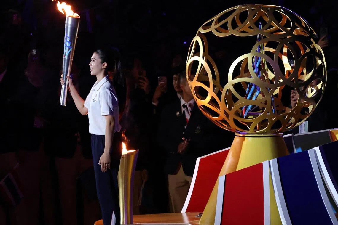泰国著名跆拳道女将翁巴达那吉（左）是最后一棒火炬手，她身后的则是主火炬的点火装置，装置上的圆圈代表着参赛的11个国家。（路透社）