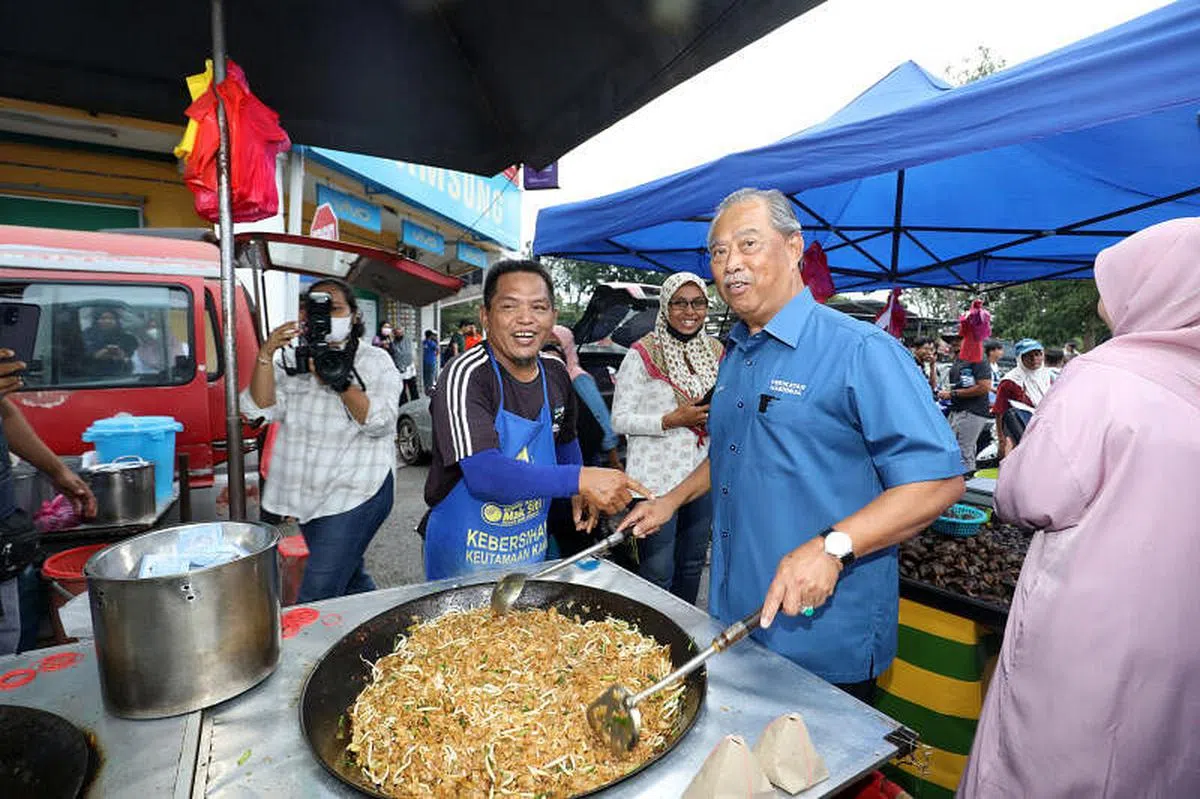 马国政治人物竞选期间扫街拜票时，往往必须精通“十八般武艺”。图为前首相及国盟主席慕尤丁11月9日在柔佛麻坡的巴莪再也花园夜市竞选时，一时兴起就帮夜市小贩炒起粿条。慕尤丁也是国盟巴莪区国会议员候选人。（邝启聪摄）