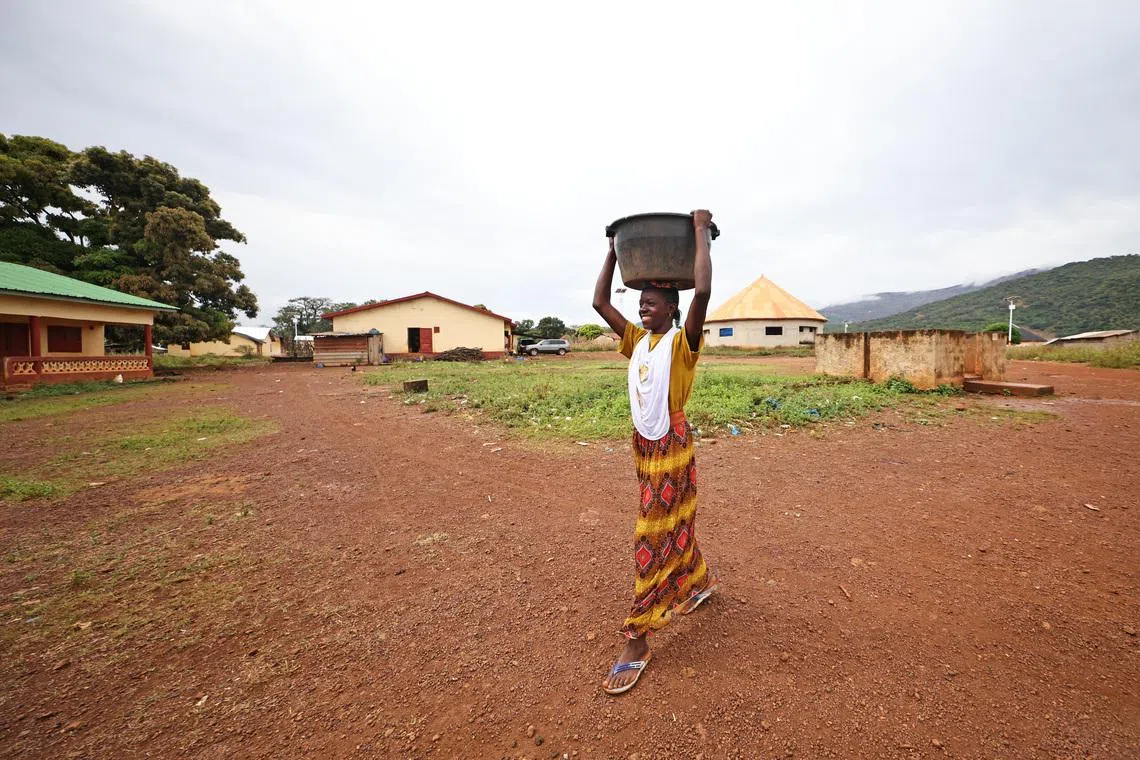几内亚有过半人口住在农村，图为一位女性用头顶着一个器皿，这类器皿一般用来盛放他们的“大锅饭”。在几内亚，女性用头“扛”物品很常见。（陈渊庄摄）