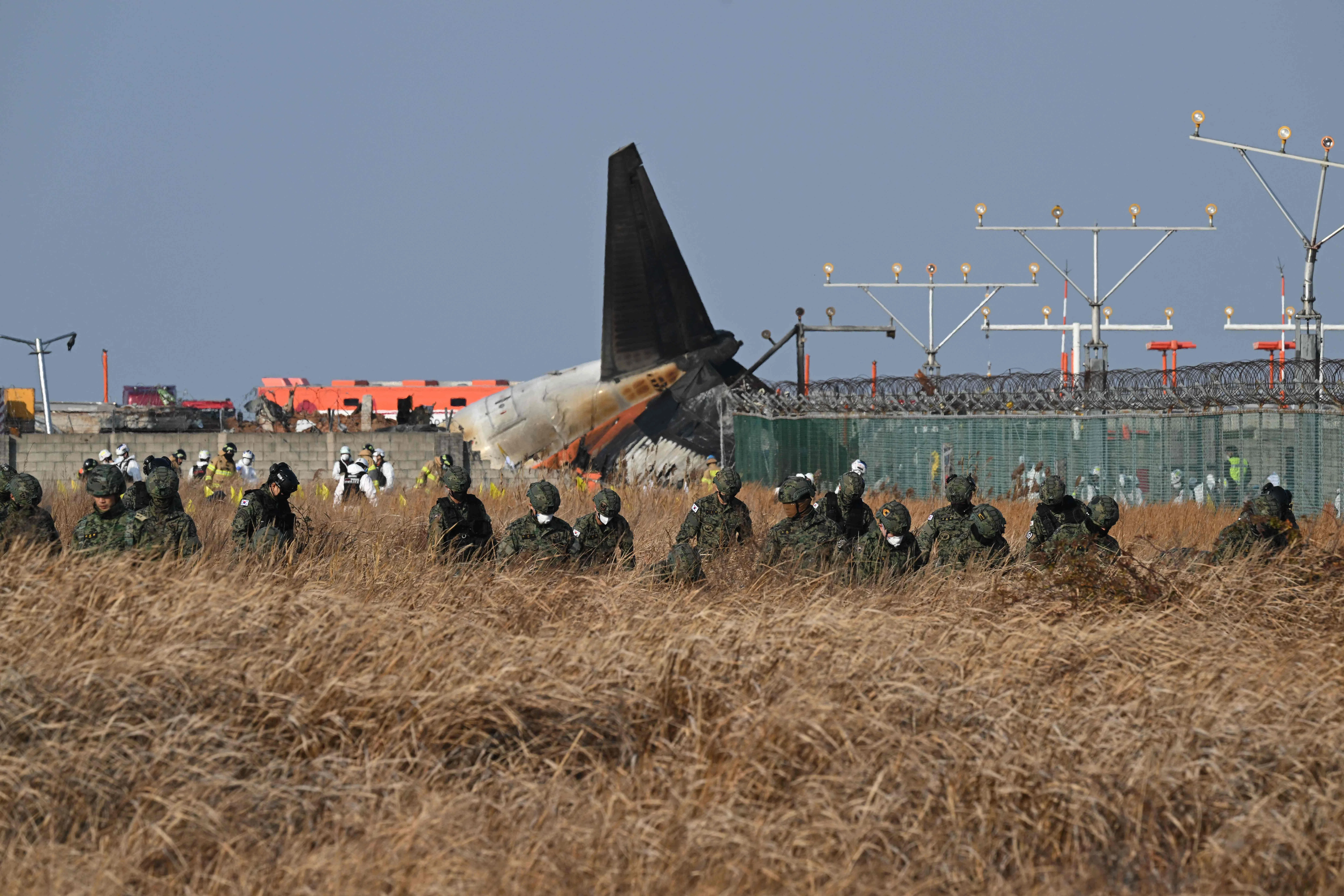 韩国士兵在坠机现场附件的草丛中搜寻失踪乘客。（法新社）