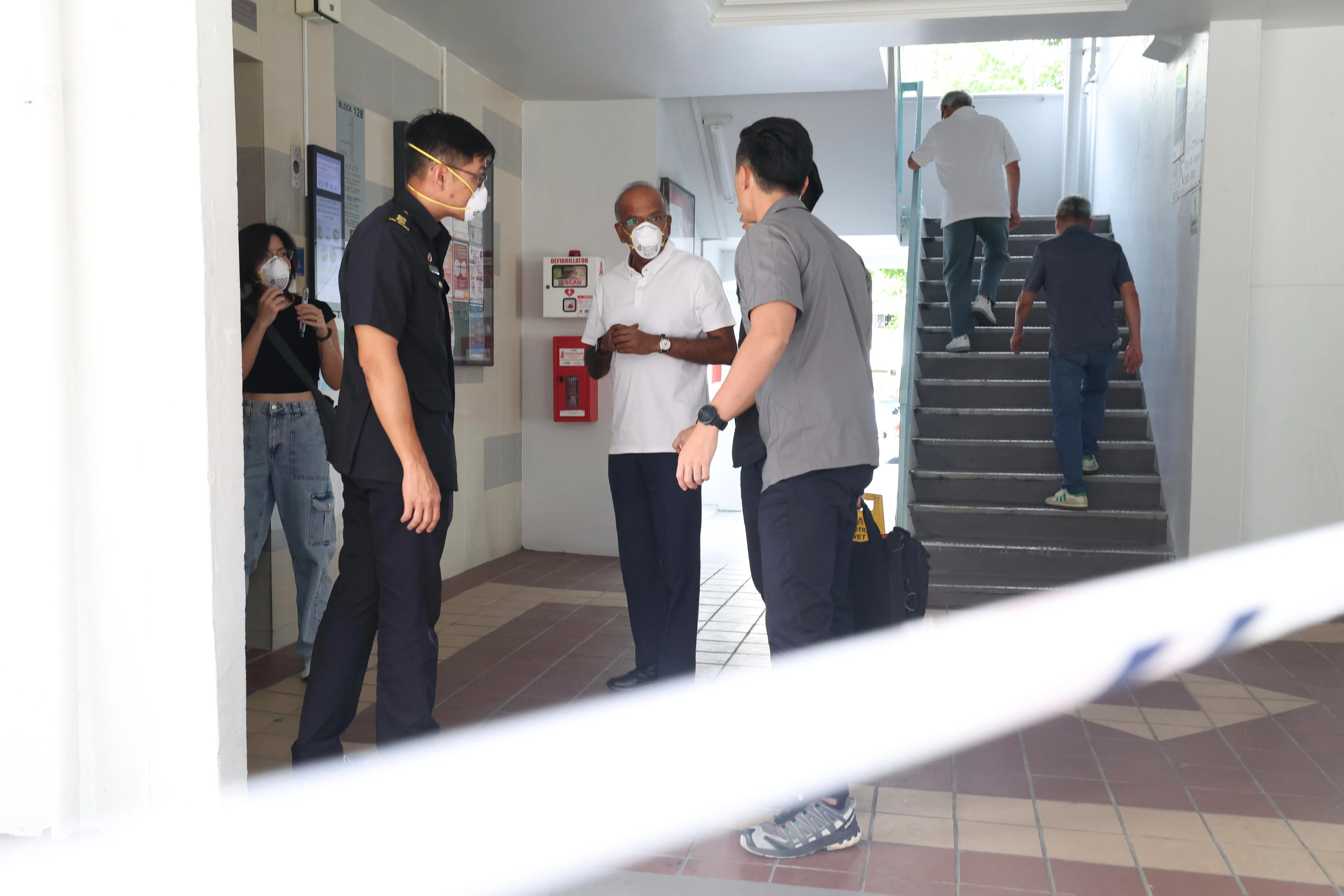 尚穆根向在场的民防人员和警方了解情况后，在他们的陪同下上楼查看失火单位。（郑一鸣摄）