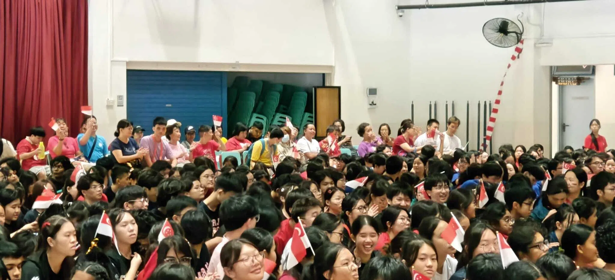 来自MINDS Me Too! Club康乐俱乐部的参与者与安德逊实龙岗初院师生欢聚一堂，挥舞国旗，高唱国庆歌曲。（安德逊实龙岗初院提供）