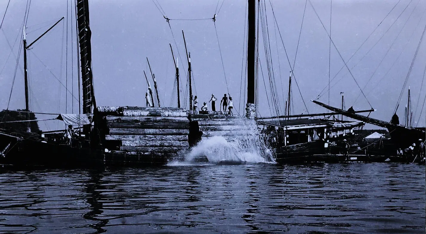 载木桐的船抵达独立桥附近河面，工人解开束带，木桐滚下，激起水花，恢复平静之后，这些木头沿河被拉到加冷的锯木厂。（雷福胜摄）