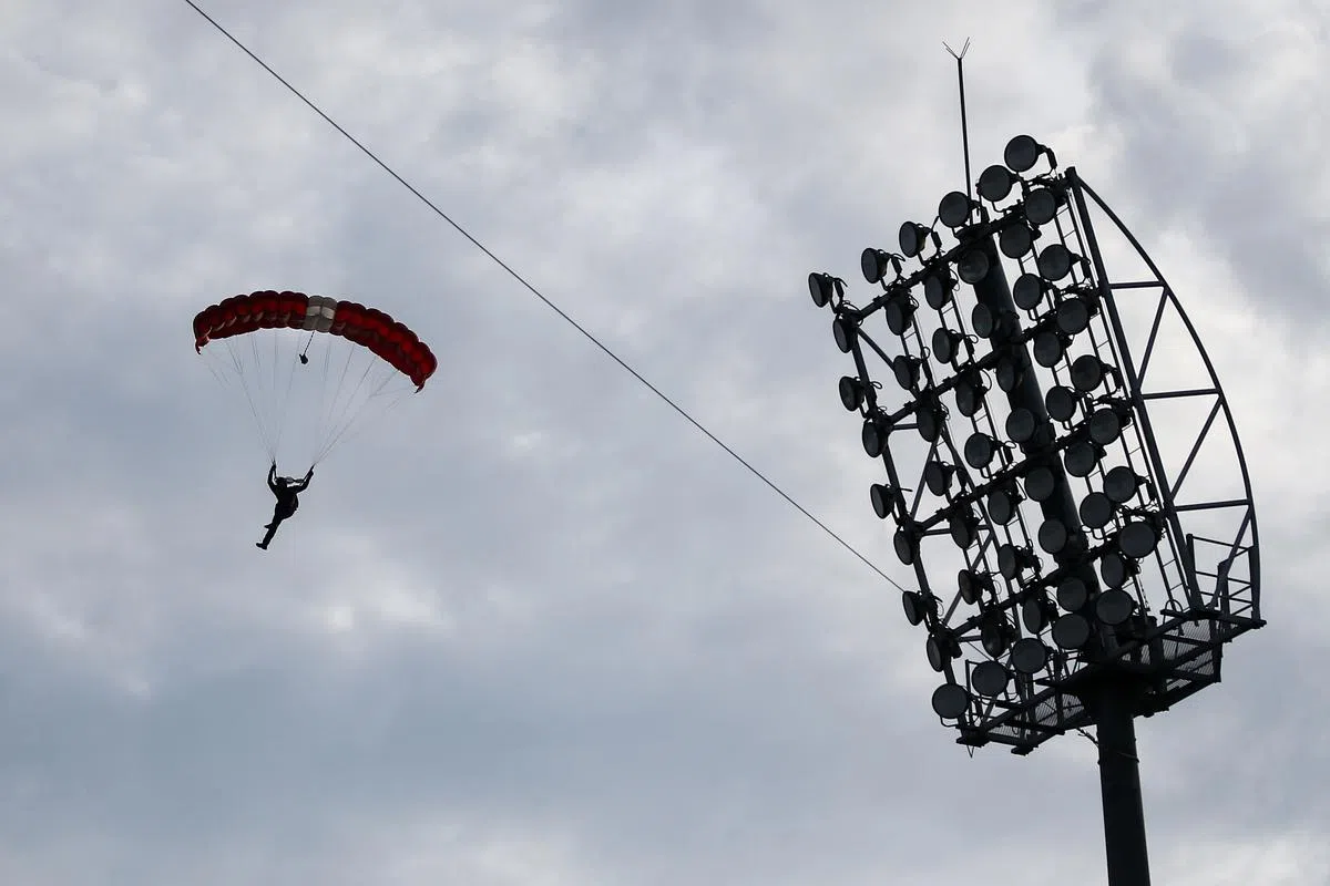 万众期待的红狮跳伞队今天终于登场，观众除了一一降落的五名红狮队员，也兴奋地拿出手机拍摄他们的英姿。（陈渊庄摄）