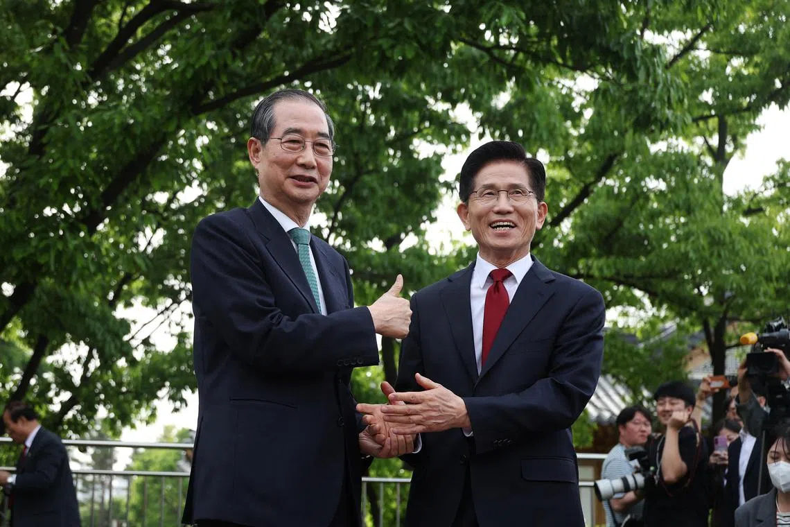 韩国执政的国民力量党候选人金文洙（右）与无党籍候选人、前总理韩悳洙星期四在首尔国会户外庭院就“单一化”议题展开协商。（路透社）