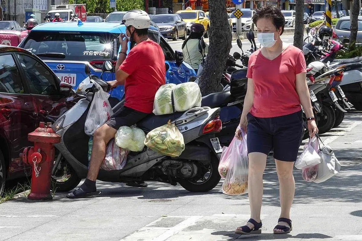 一名男子所骑电单车的手把、踏板及后座几乎都堆置蔬果。（中时新闻网）