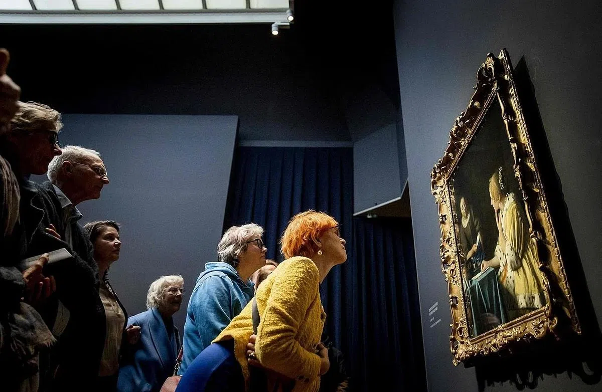 访客在荷兰国立博物馆聚精会神地观看画家扬·维米尔的作品《情妇与女仆》。（法新社）