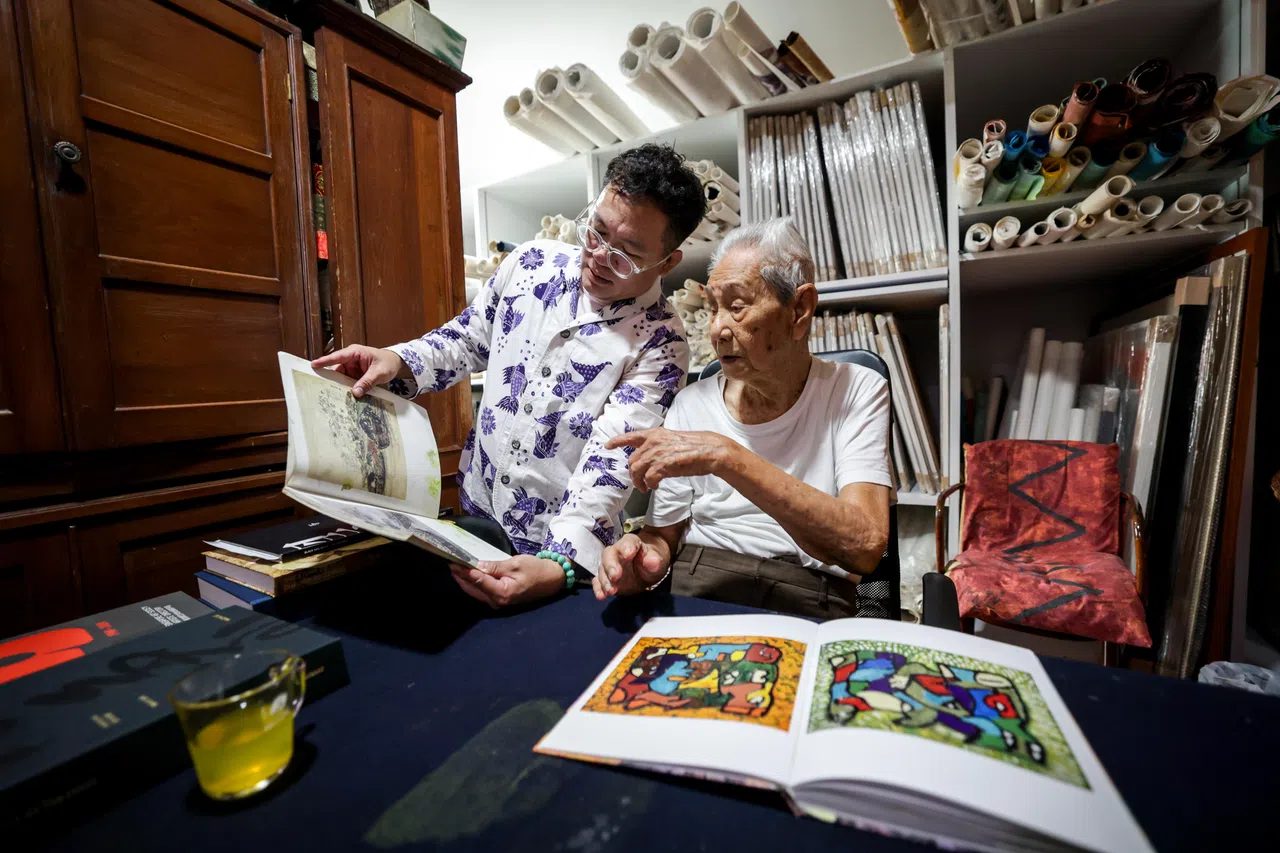 林子平与编导一同端详画册。画家晚年拿出旧画重新创作，往往能得出意想不到的新意。（叶振忠摄）