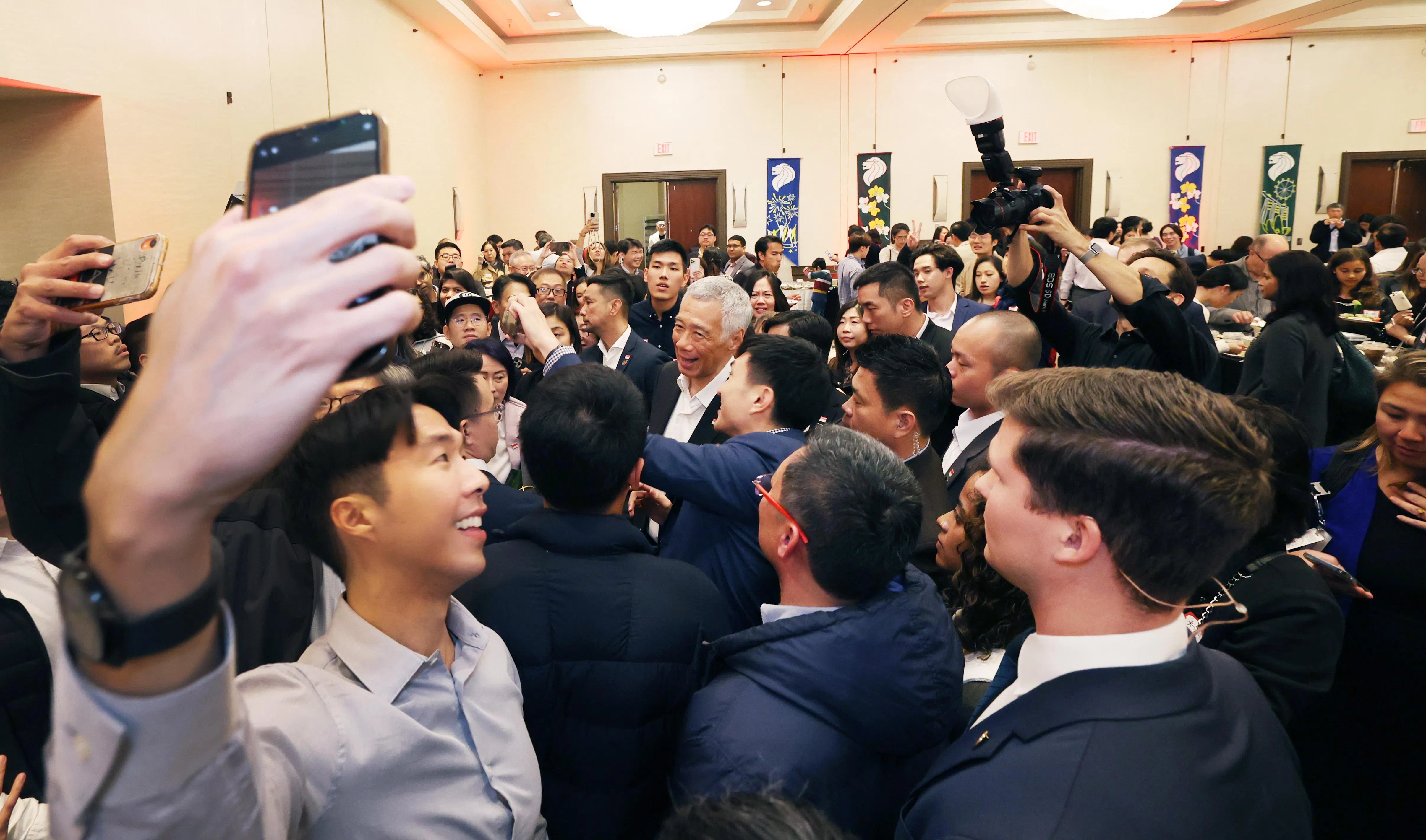 出席招待会的新加坡人排队与李总理（中）合照。他们也在招待会上享用了丰盛的新加坡美食，如咖喱卜、鸡饭、福建虾面、椰浆饭和沙爹。（邝启聪摄）