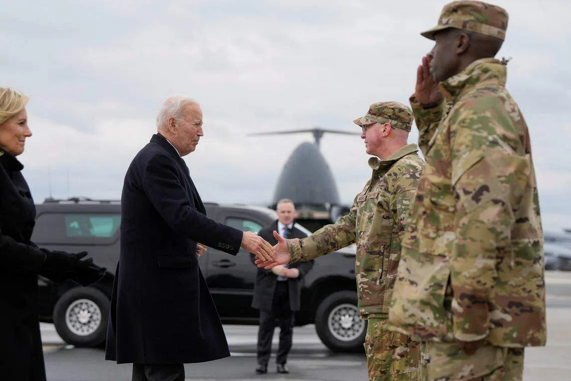 拜登（左前）与夫人吉尔在多佛空军基地迎接从约旦运返回国的三名殉职士兵的灵柩，并与一同出席仪式的美军将领握手。（路透社）