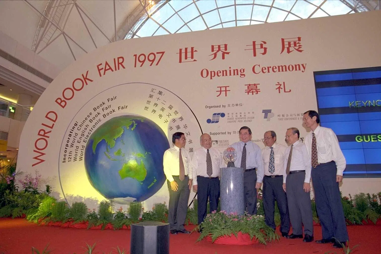 1997年6月20日，时任教育部高级政务部长陈敏良（左三）为第12届世界书展揭开序幕。左起为书展协办主席廖国斌、时报出版执行副总裁任正君、报业控股业务总裁郑坤德、报业控股华文报集团总经理周景锐以及书展工委会主席萧作鸣。（档案照片）